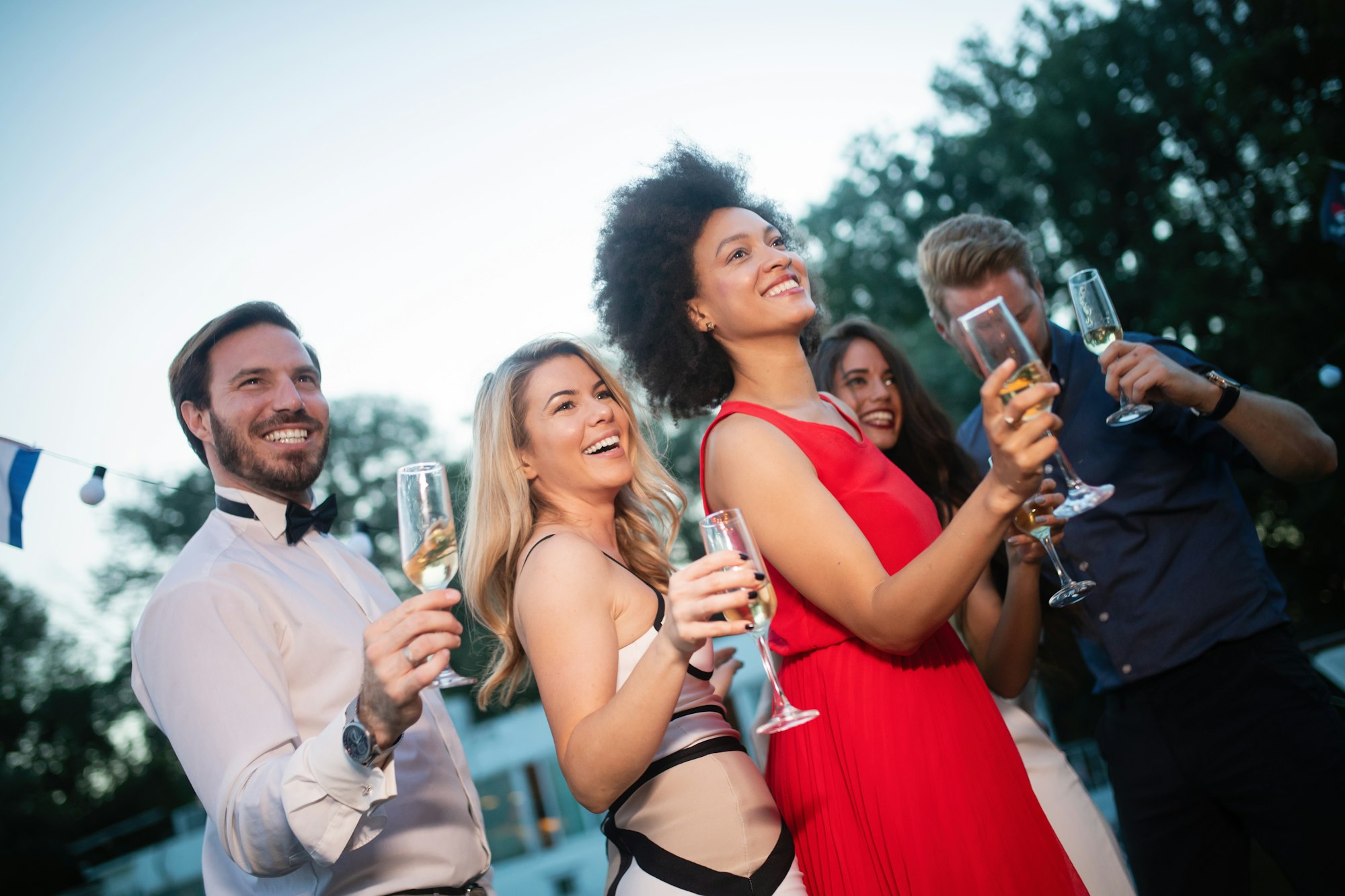 Group of friends drinking, chatting and having a fun at outdoor party